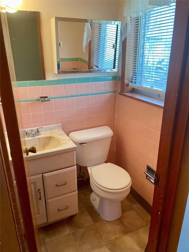 bathroom with tile patterned floors, vanity, tile walls, and toilet