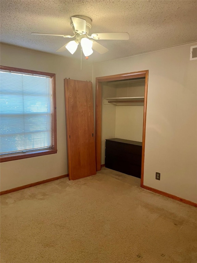 unfurnished bedroom with light carpet, a textured ceiling, a closet, and ceiling fan