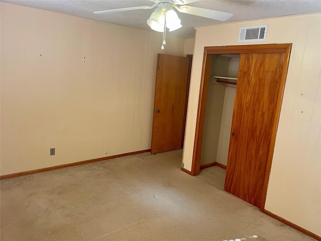 unfurnished bedroom featuring ceiling fan, a textured ceiling, light carpet, and a closet