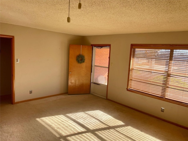 spare room featuring light colored carpet and a textured ceiling