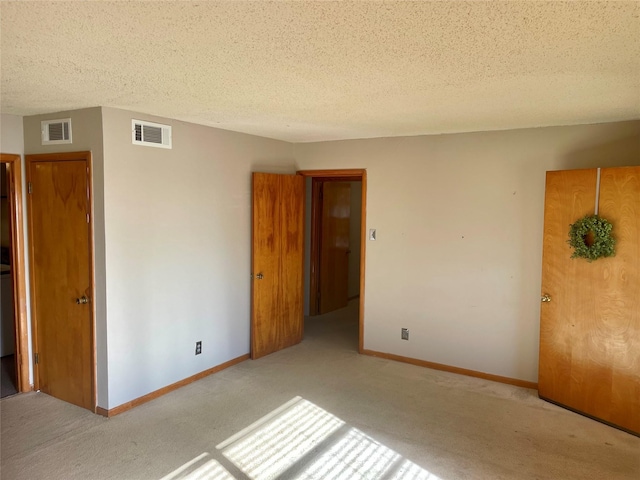 carpeted empty room featuring a textured ceiling