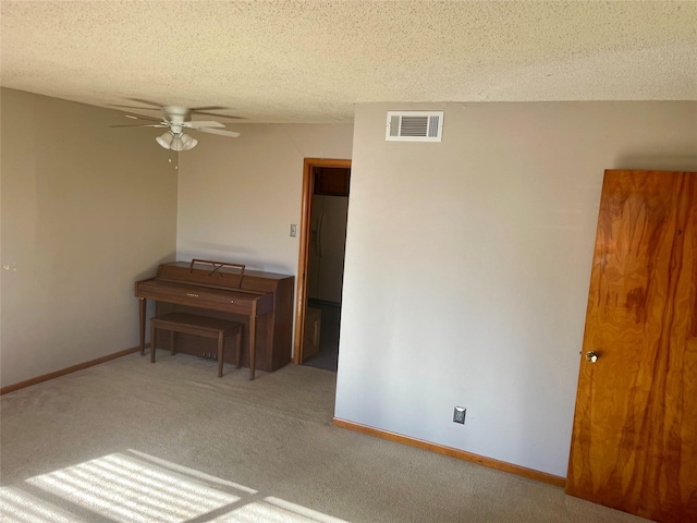 carpeted empty room with ceiling fan and a textured ceiling