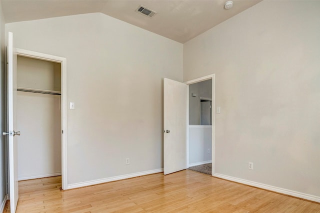 unfurnished bedroom with a closet, light hardwood / wood-style floors, and vaulted ceiling