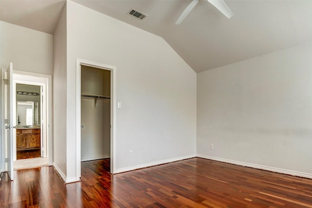 unfurnished bedroom with dark hardwood / wood-style flooring, a walk in closet, ceiling fan, a closet, and lofted ceiling