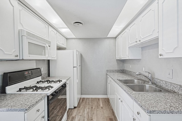 kitchen featuring white appliances, white cabinetry, and a sink