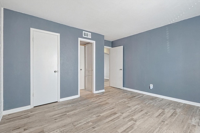 unfurnished bedroom featuring baseboards, visible vents, and wood finished floors