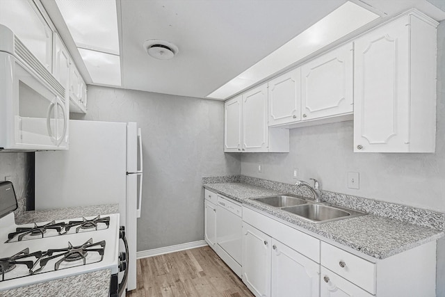 kitchen featuring light wood-style flooring, white appliances, a sink, white cabinetry, and light countertops