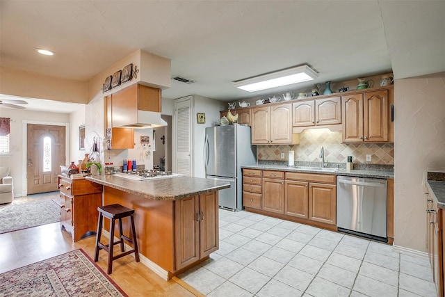 kitchen with stainless steel appliances, decorative backsplash, a kitchen bar, ceiling fan, and sink