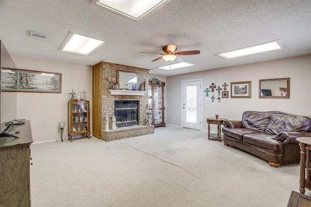 living room with a textured ceiling, ceiling fan, light carpet, and a fireplace