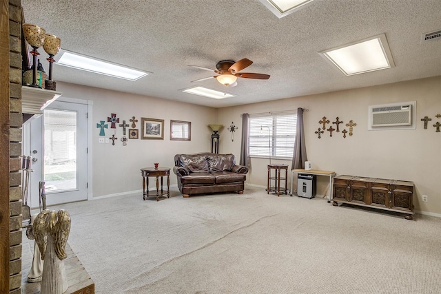 living area featuring a wall unit AC, a textured ceiling, ceiling fan, and carpet