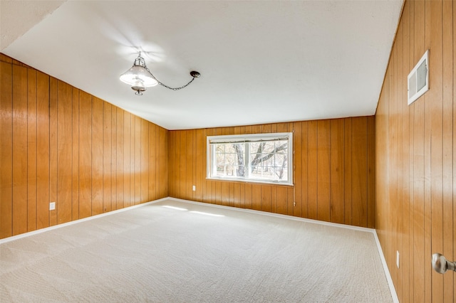 spare room featuring carpet and wooden walls