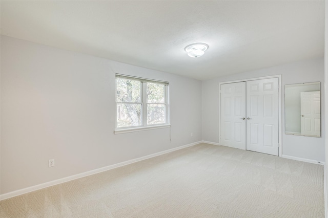 unfurnished bedroom with light colored carpet and a closet