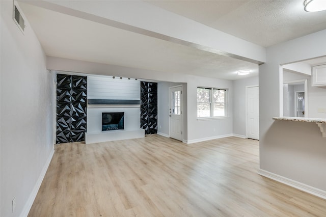 unfurnished living room featuring light hardwood / wood-style floors and a textured ceiling