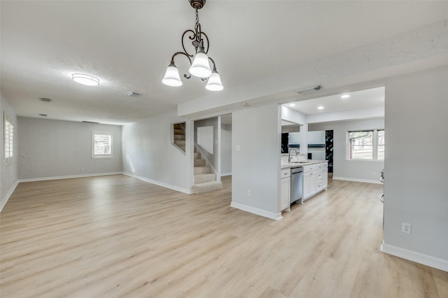 kitchen featuring pendant lighting, sink, stainless steel dishwasher, light hardwood / wood-style floors, and white cabinetry