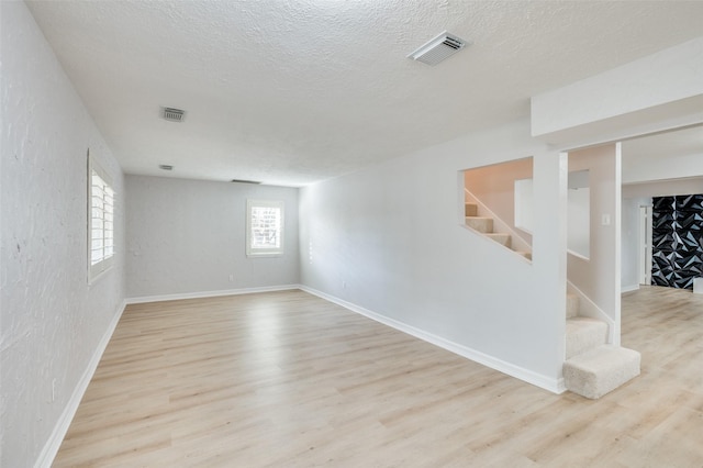 basement with light wood-type flooring and a textured ceiling