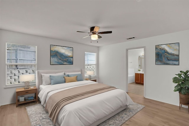 bedroom with ensuite bathroom, light wood-type flooring, and ceiling fan