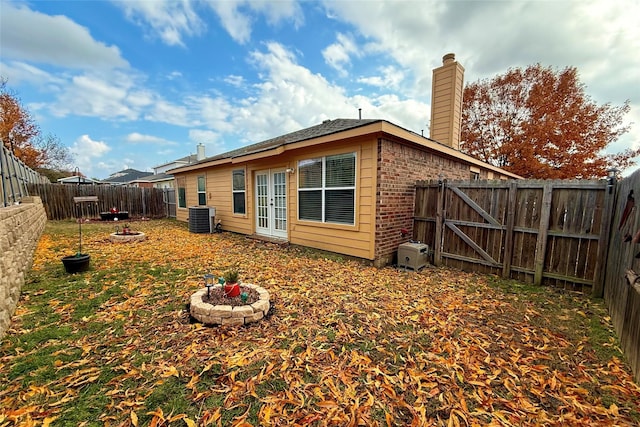 view of side of home with french doors, central AC unit, and an outdoor fire pit