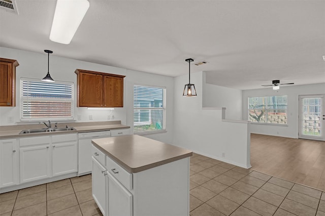 kitchen with sink, a center island, light tile patterned floors, dishwasher, and pendant lighting