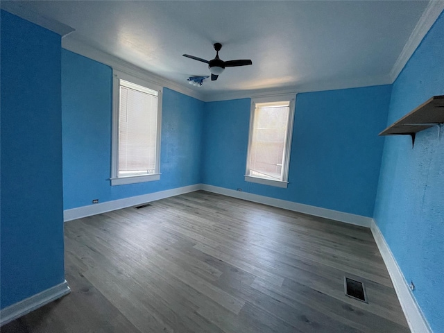 empty room with crown molding, ceiling fan, a healthy amount of sunlight, and dark wood-type flooring