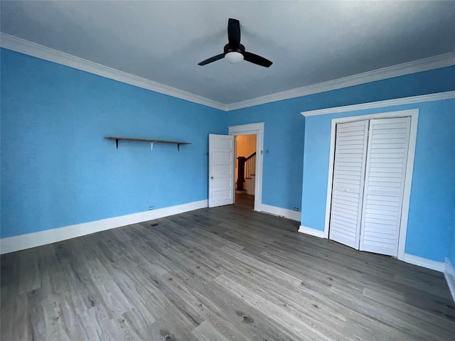 unfurnished bedroom featuring hardwood / wood-style floors, a closet, ceiling fan, and crown molding