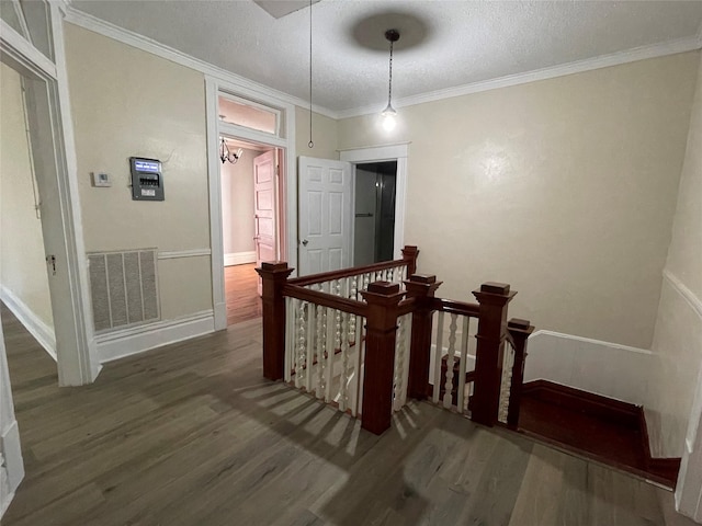 hall with crown molding, dark wood-type flooring, and a textured ceiling