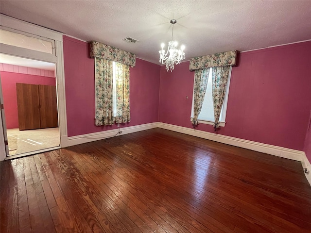 unfurnished room with an inviting chandelier, a textured ceiling, and hardwood / wood-style flooring