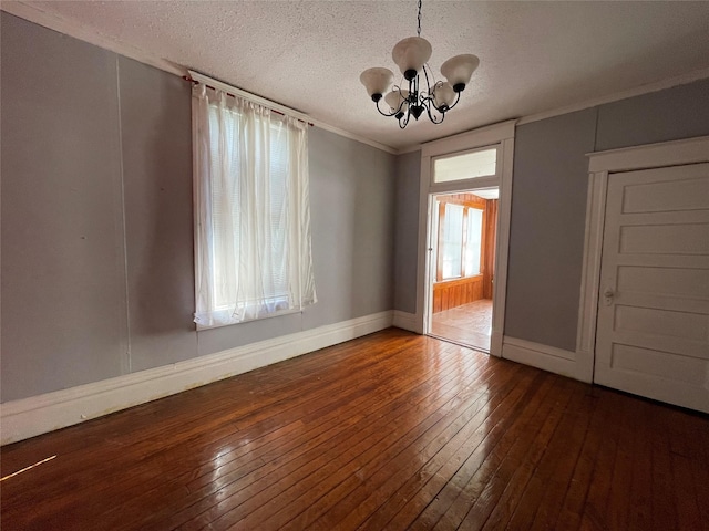 spare room with dark hardwood / wood-style flooring, ornamental molding, a textured ceiling, and an inviting chandelier