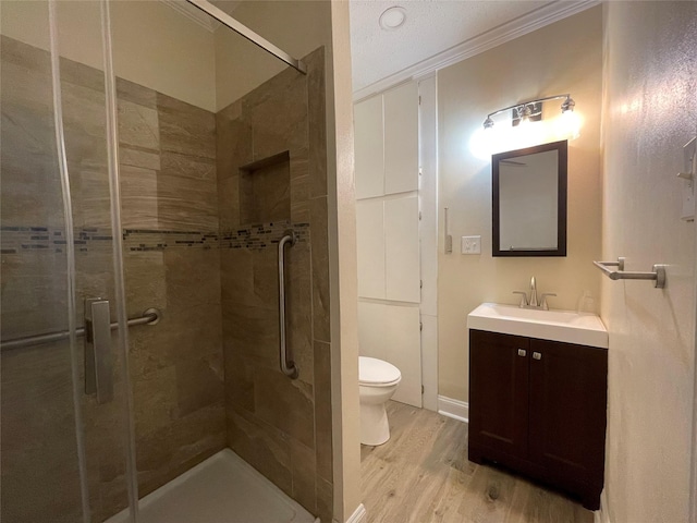 bathroom featuring vanity, toilet, ornamental molding, an enclosed shower, and wood-type flooring