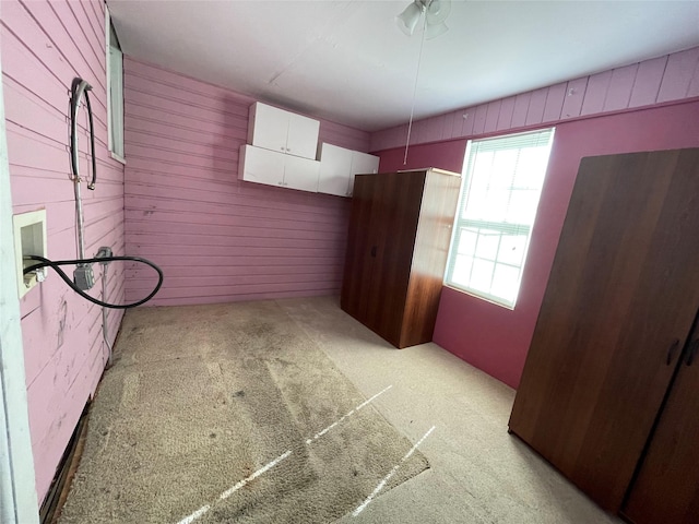 unfurnished room with light colored carpet and wood walls