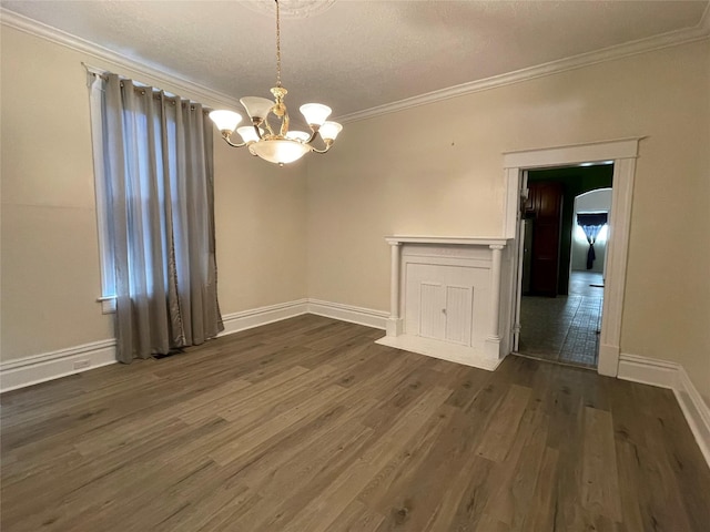 unfurnished dining area with a chandelier, a textured ceiling, crown molding, and dark wood-type flooring