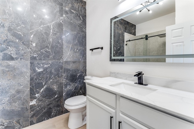 bathroom with a tile shower, vanity, and toilet