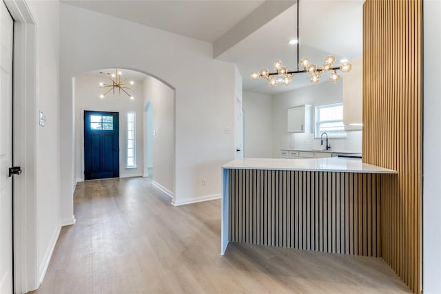 entryway with sink, a chandelier, and light wood-type flooring