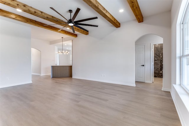 empty room featuring beam ceiling, ceiling fan with notable chandelier, and light wood-type flooring