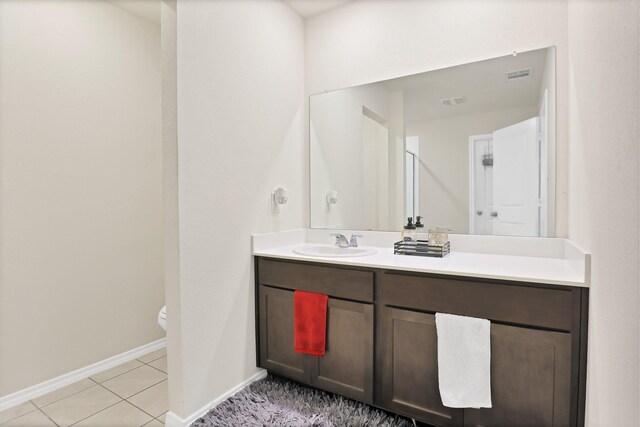 bathroom with toilet, vanity, and tile patterned flooring