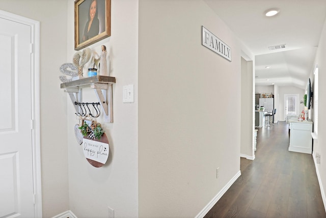 corridor with dark hardwood / wood-style floors and vaulted ceiling