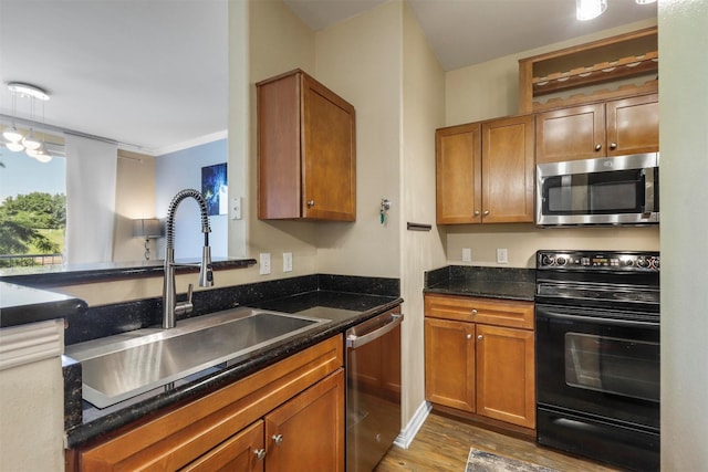 kitchen featuring crown molding, sink, dark stone countertops, wood-type flooring, and stainless steel appliances