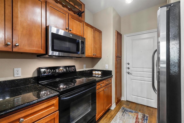 kitchen with dark hardwood / wood-style flooring, stainless steel appliances, and dark stone counters