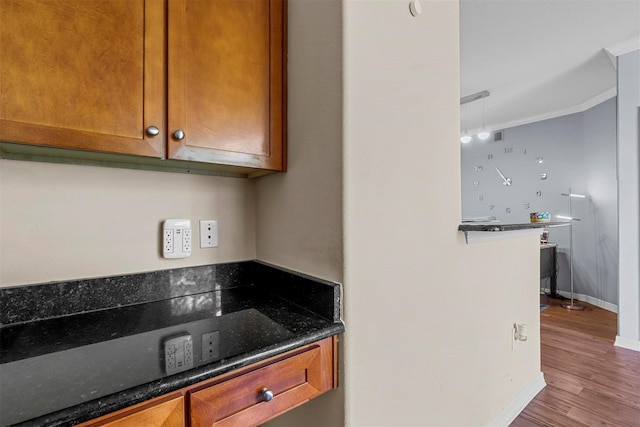 kitchen featuring dark stone countertops, hardwood / wood-style floors, and ornamental molding