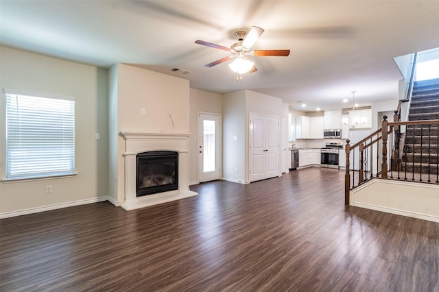 unfurnished living room with a wealth of natural light, dark hardwood / wood-style floors, and ceiling fan