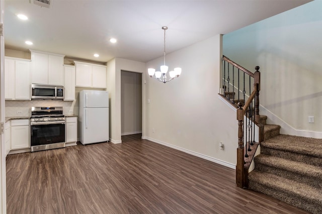 kitchen with white cabinets, dark hardwood / wood-style flooring, stainless steel appliances, and tasteful backsplash