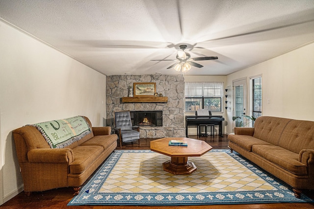 living room with ceiling fan, dark wood-type flooring, crown molding, a textured ceiling, and a fireplace