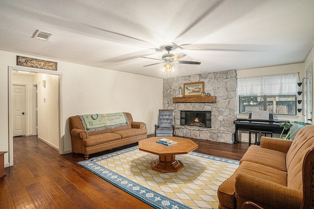 living room featuring a textured ceiling, ceiling fan, dark hardwood / wood-style flooring, and a fireplace