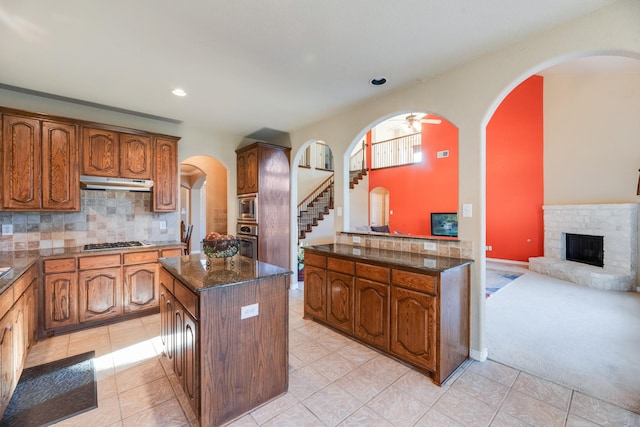 kitchen with backsplash, stainless steel appliances, ceiling fan, light tile patterned floors, and a kitchen island