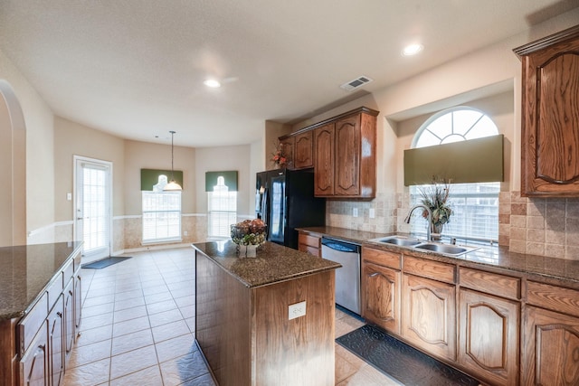 kitchen featuring dishwasher, black fridge, sink, light tile patterned floors, and a kitchen island