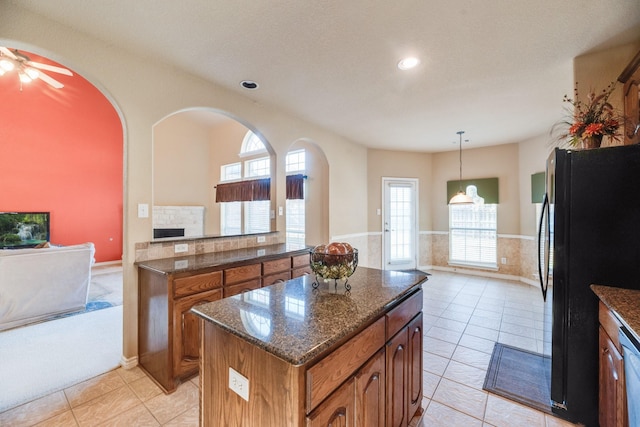 kitchen featuring black refrigerator, light tile patterned floors, decorative light fixtures, and a kitchen island