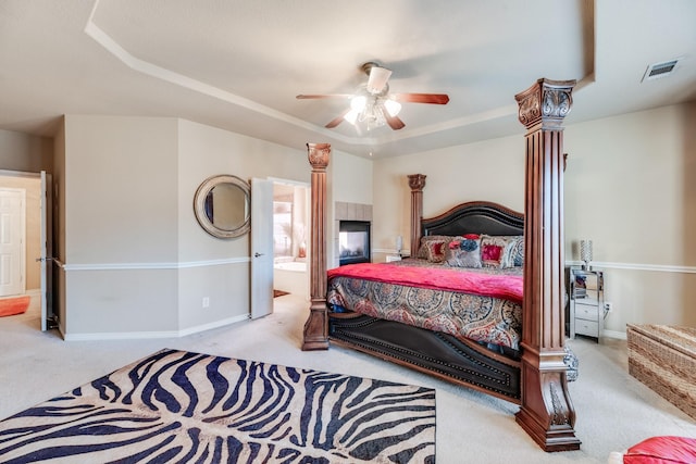 carpeted bedroom with a tray ceiling, ensuite bathroom, and ceiling fan