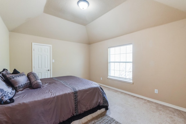 bedroom featuring vaulted ceiling, light colored carpet, and a raised ceiling