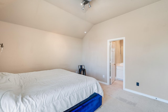 bedroom featuring ensuite bathroom, vaulted ceiling, and light colored carpet