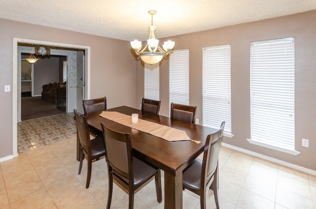 dining area featuring a chandelier, a textured ceiling, and light tile patterned flooring