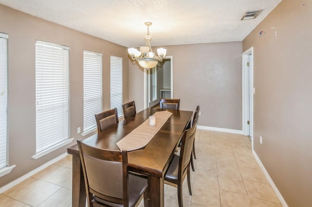 tiled dining area with a textured ceiling and a notable chandelier